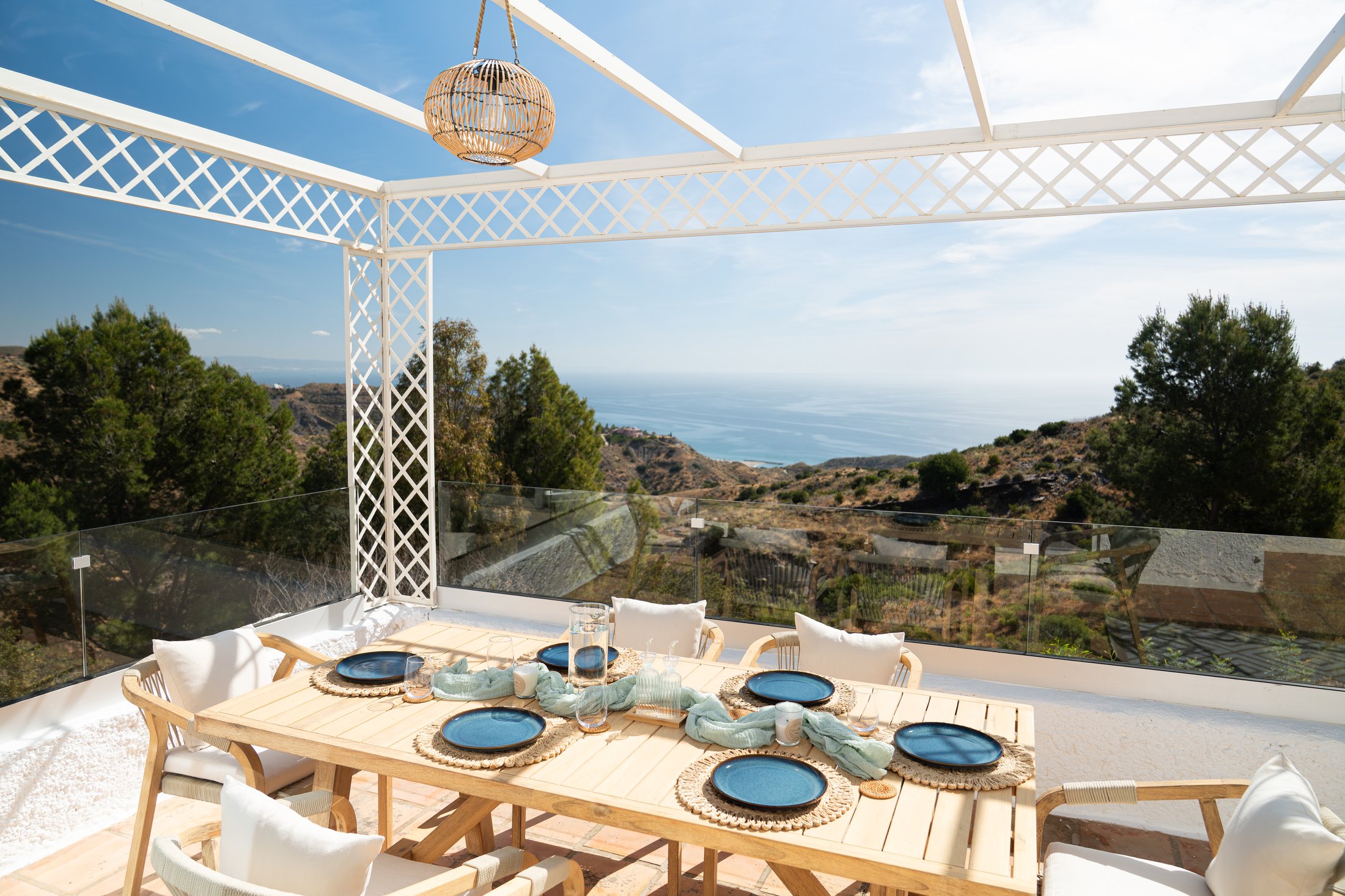 A table laid under the pergola at Alma Azul, the Mediterranean beyond